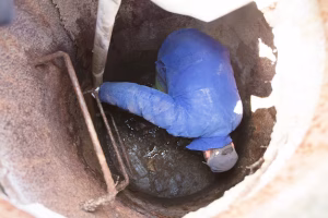 Worker cleaning sewer hatch to prevent summer sewage problems in Vancouver WA